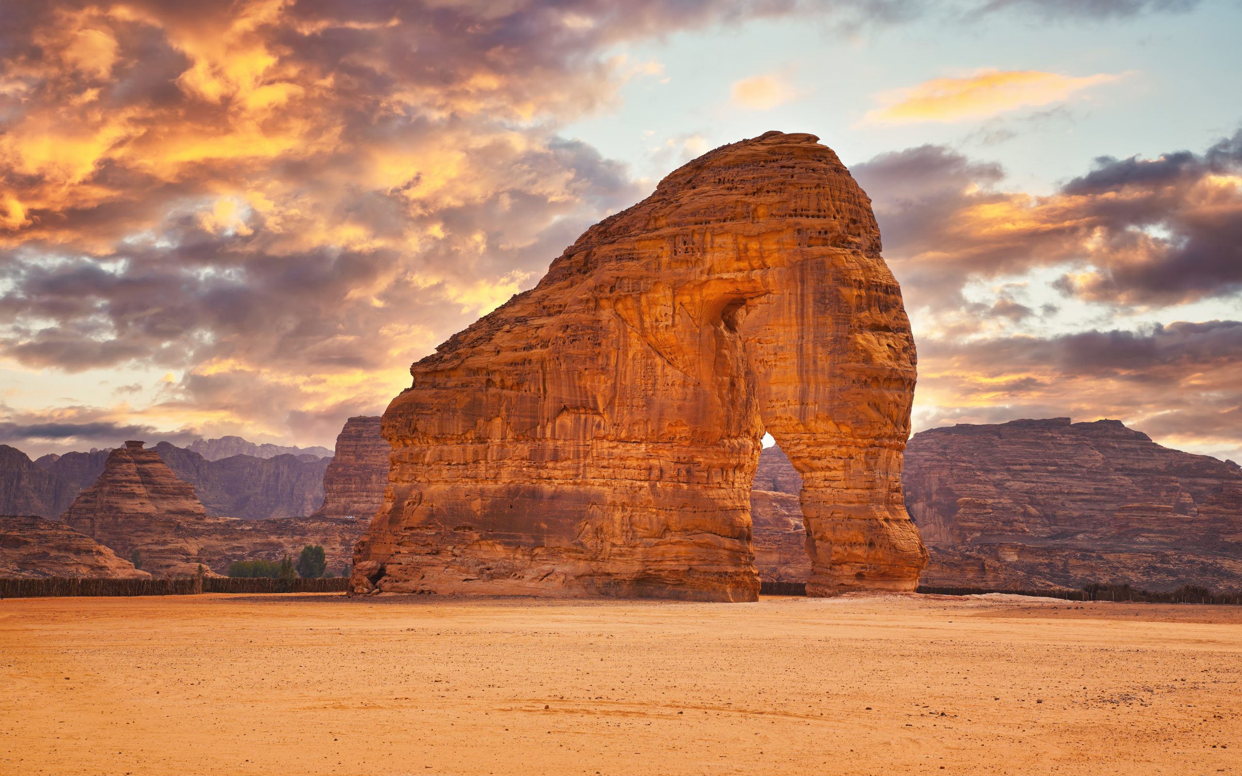 Jabal AlFil - Elephant Rock in Al Ula desert landscape, dramatic sunset sky above - Saudi Arabia